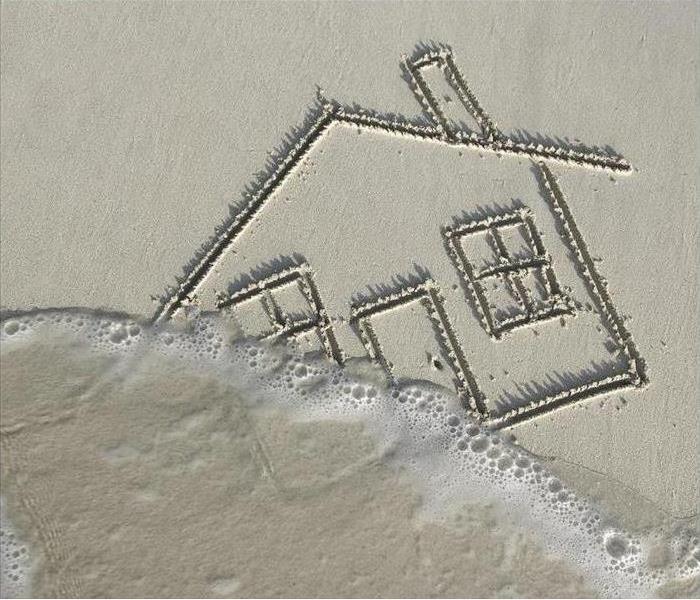 Drawing in the sand of a house with the waves washing over it. 