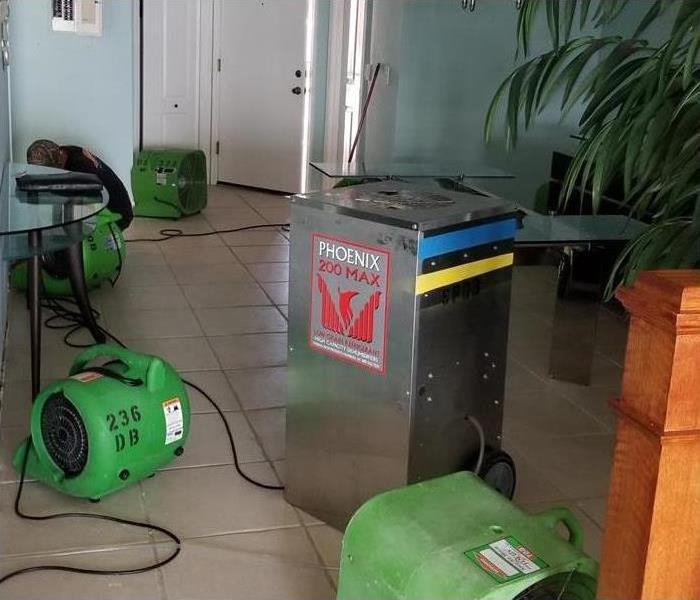 Air Movers drying a tile floor and drywall after water damage.